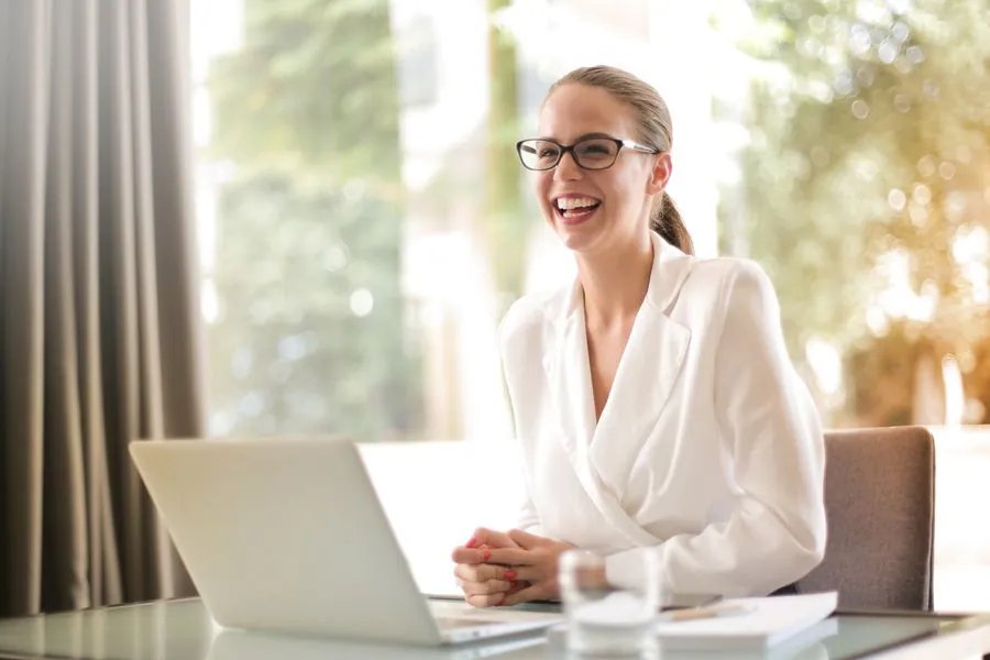 Cliente souriante et soulagée devant son ordinateur portable après son dépannage