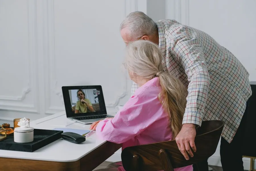 Un couple de seniors en visioconférence avec leur fille, qui veille sur eux à distance