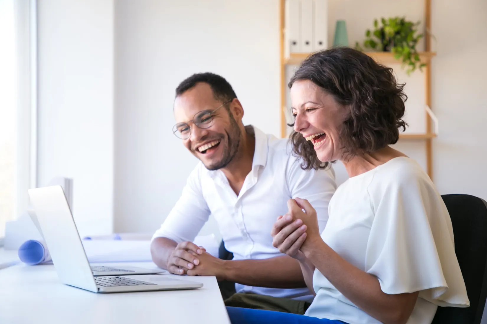 Deux clients ravis rient devant leur ordinateur portable pendant leur dépannage en visio