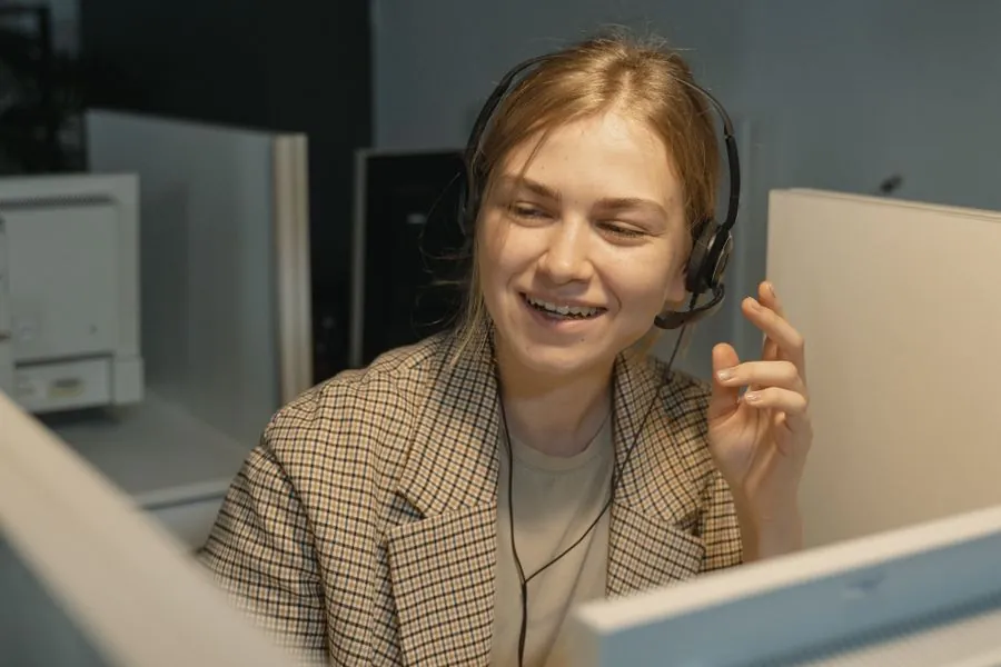 Conseillère Helpers souriante avec un casque, en train de dépanner un client à distance
